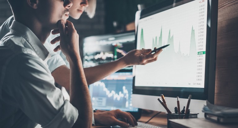 Analyzing data. Close-up of young business team working together in creative office while young woman pointing on the data presented in the chart with pen